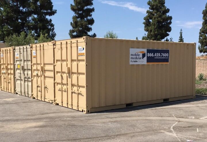 A row of portable storage containers side by side on concrete pavement