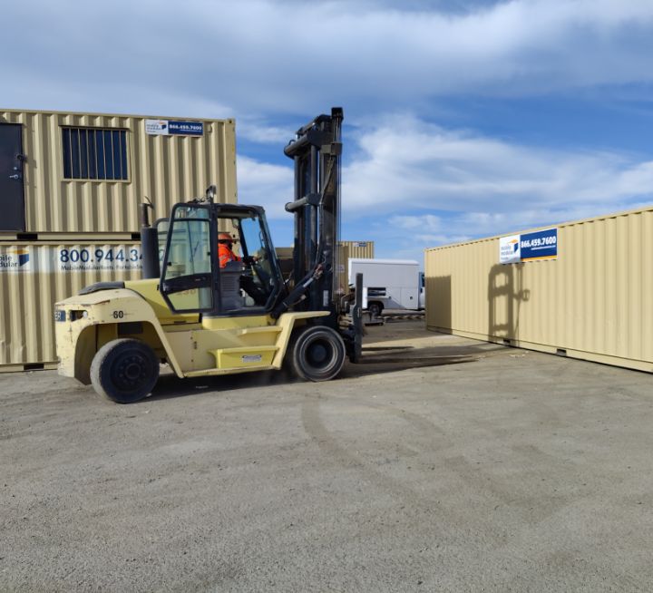 man operating forklift in front of shipping containers at the worksite