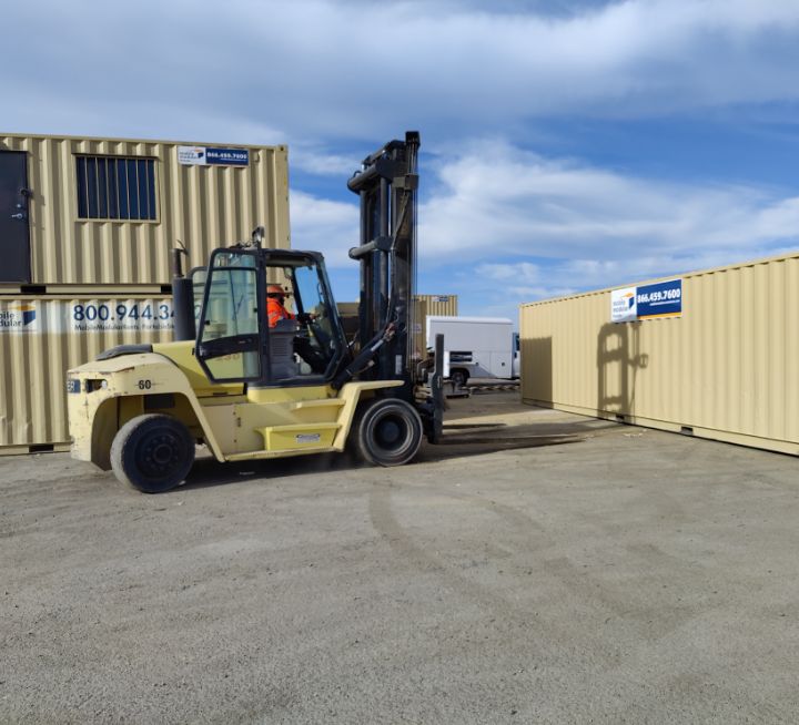 man operating forklift in front of shipping containers at the worksite