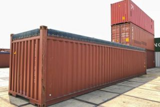 An open top container near cargo ships